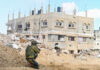 Soldier crouching near damaged building in urban area