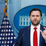 Man speaking at podium with American flag behind