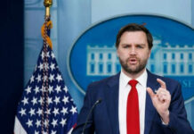 Man speaking at podium with American flag behind