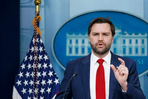 Man speaking at podium with American flag behind