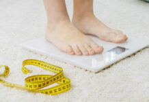 Person standing on a digital scale with a measuring tape nearby