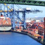A cargo ship loaded with colorful containers docked at a busy shipping port