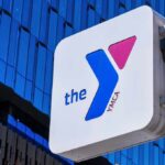 YMCA sign mounted on a modern glass building