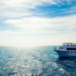Boat on open sea with blue sky overhead