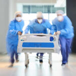 A Deadly Threat Just Reached Europe Medical team in PPE rushing a patient on a hospital gurney