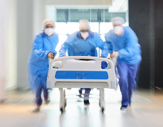 Medical team in PPE rushing a patient on a hospital gurney