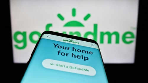 Smartphone displaying GoFundMe app with logo background