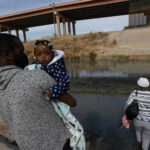 Man carrying child near a body of water