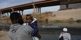 Man carrying child near a body of water