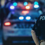 When Safe Streets Stop Feeling Safe Police officer standing near patrol car with lights