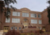 Historic brick school building with arched entrance and large white-framed windows