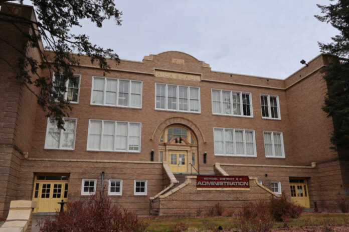 Historic brick school building with arched entrance and large white-framed windows