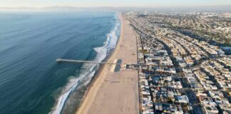Aerial view of a beach with a pier and urban area beside the ocean
