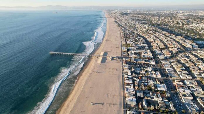 Aerial view of a beach with a pier and urban area beside the ocean