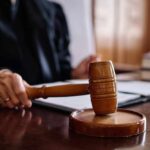 A judge's hand holding a gavel in a courtroom setting