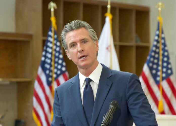 Turlock,,Ca,-,Jan,6,,2025:,Ca,Governor,Gavin,Newsom A government official speaking at a podium with American flags in the background