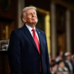 How Much Should Washington Really Know? A man in a suit smiling while standing at a podium in a formal setting