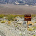 One Park, Four Days, Three Deaths Warning sign about extreme heat in a rocky desert landscape