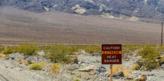 Warning sign about extreme heat in a rocky desert landscape