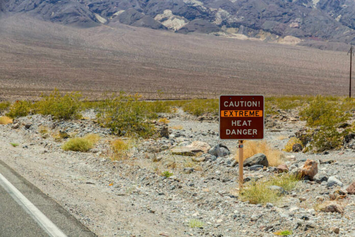 Warning sign about extreme heat in a rocky desert landscape