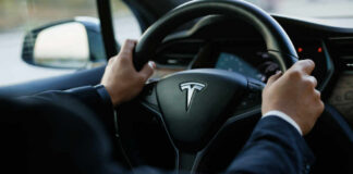 Tesla steering wheel held by driver in a car interior