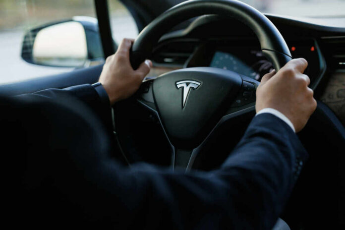 Tesla steering wheel held by driver in a car interior