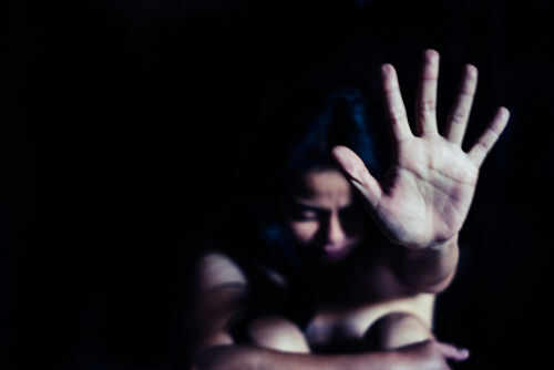 trafficking-abuse-1017715399 Person holding hand up in dark space