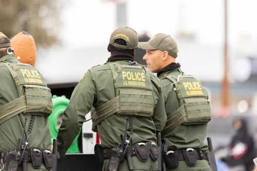 Border patrol officers standing with equipment outside