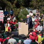 speaker at outdoor rally addressing a large crowd