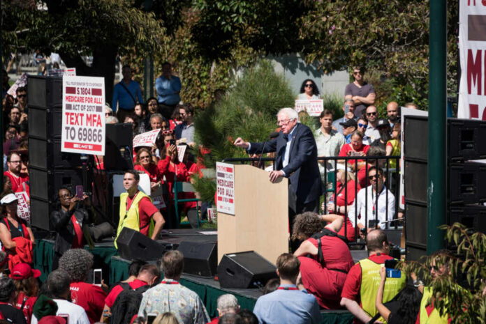 speaker at outdoor rally addressing a large crowd