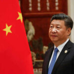 Person standing near a Chinese flag indoors