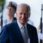 Man in suit with uniformed guards in background