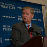 Man in suit speaking at a podium with a microphone