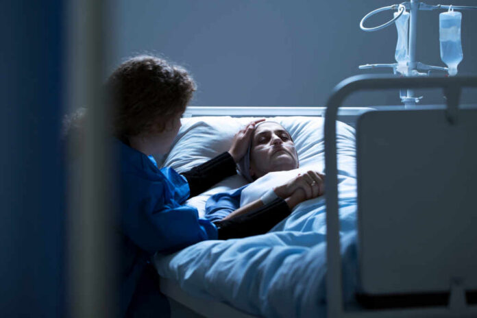 Patient in hospital bed comforted by visitor