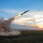 Rocket launching over a field at sunset