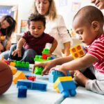 toddlers playing with colorful building blocks on a mat