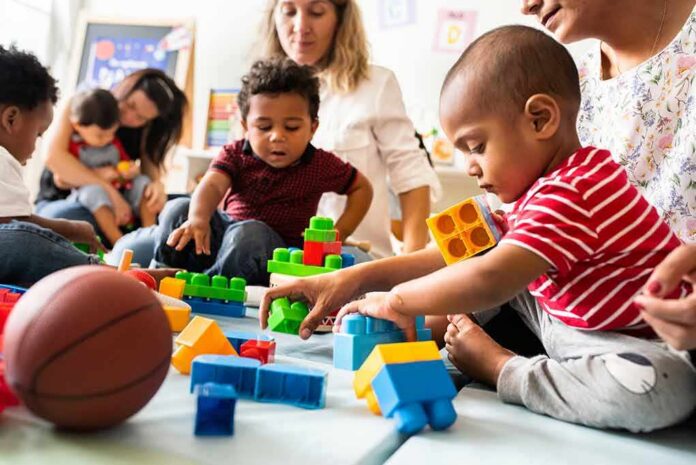 toddlers playing with colorful building blocks on a mat