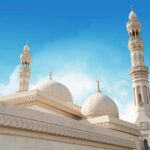 Mosque with domes and minarets against a clear blue sky