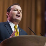 A man in a suit delivering a speech at a podium