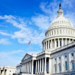 The U.S. Capitol building with an American flag flying under a blue sky