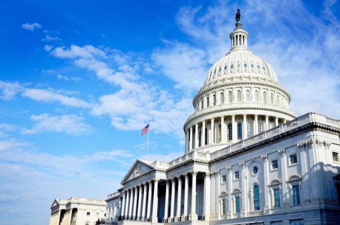 United,States,Capitol,Building,In,Whashington,Dc,With,Flag,On The U.S. Capitol building with an American flag flying under a blue sky