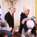 Friends, Allies… and a Major Disagreement Two suited men at a formal event with an Israeli flag and audience