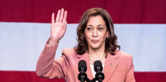 Woman raising her hand while speaking at podium.