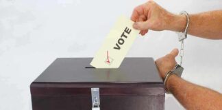 Hand in handcuffs casting a vote into a ballot box
