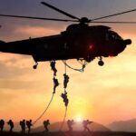 military helicopter with soldiers fast-roping at sunset