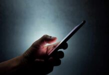 Hand holding a smartphone in the dark