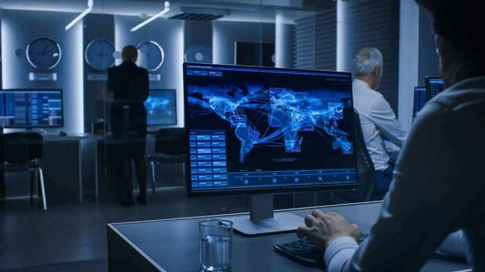 Analyst monitors world map data on large screen in control room