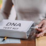 Person handling a DNA test kit with swabs on a table