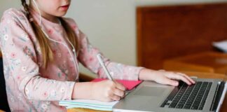 Child studying with laptop and notebook at a round table