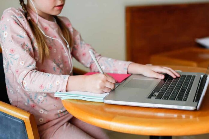 Child studying with laptop and notebook at a round table
